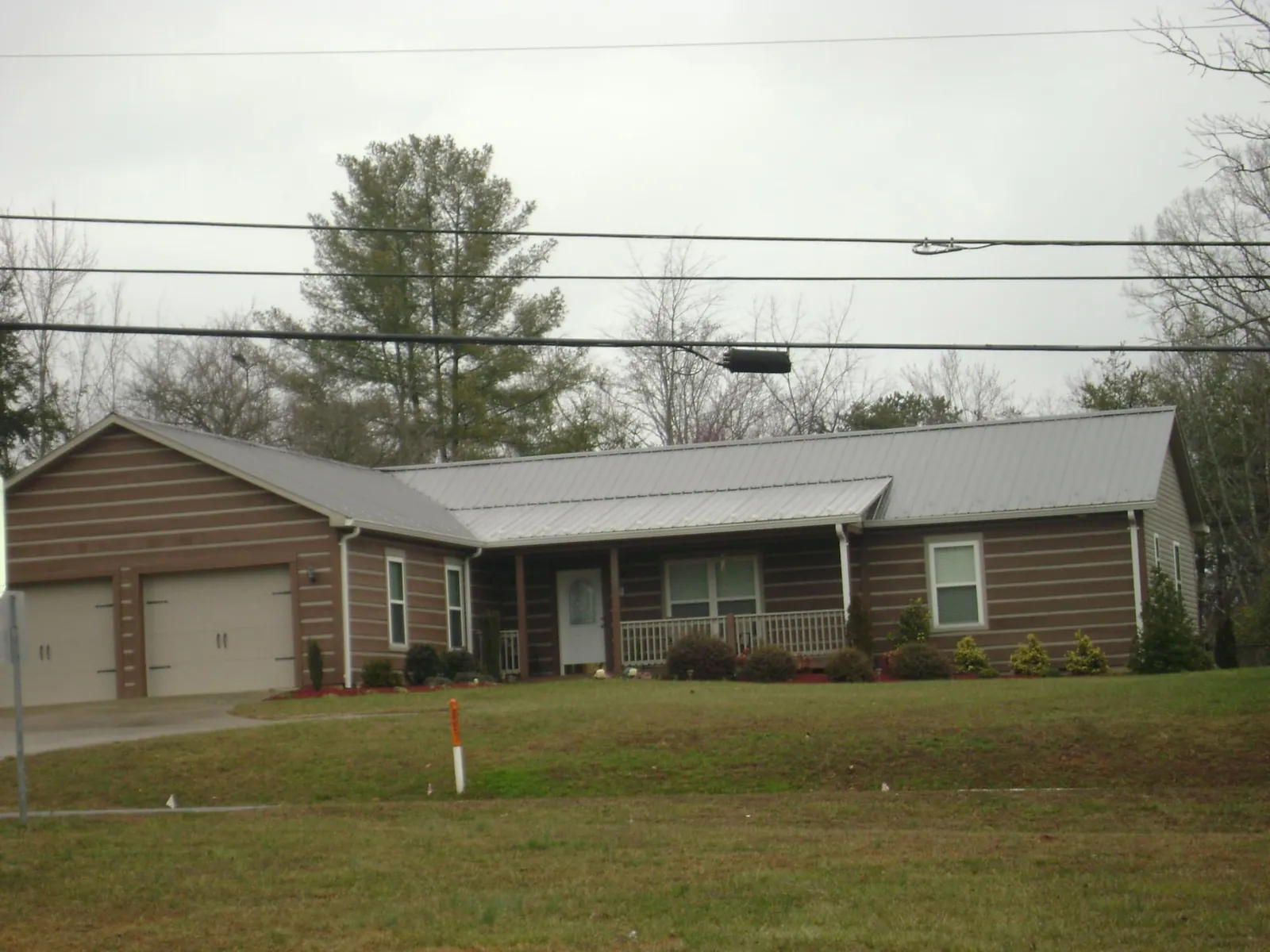 Gray metal roof on a log sided ranch home with a front porch in Goshen